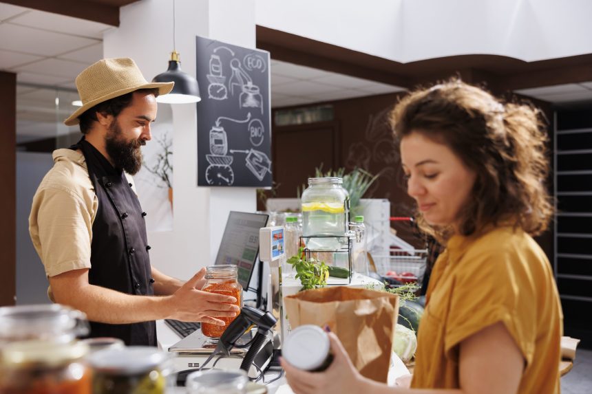 cheerful merchant checkout counter zero waste shop weighting vegan products purchased by buyer woman