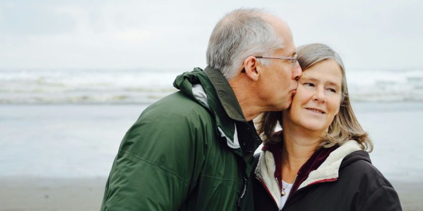 man kissing woman on check beside body of water