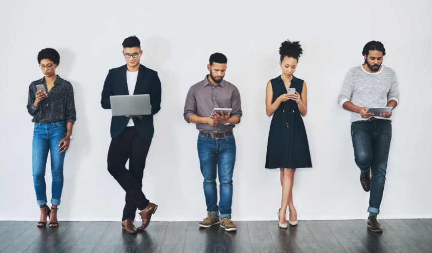Young professional people standing against a white wall using technology