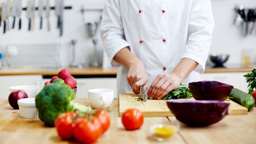 chef cutting vegetables in kitchen